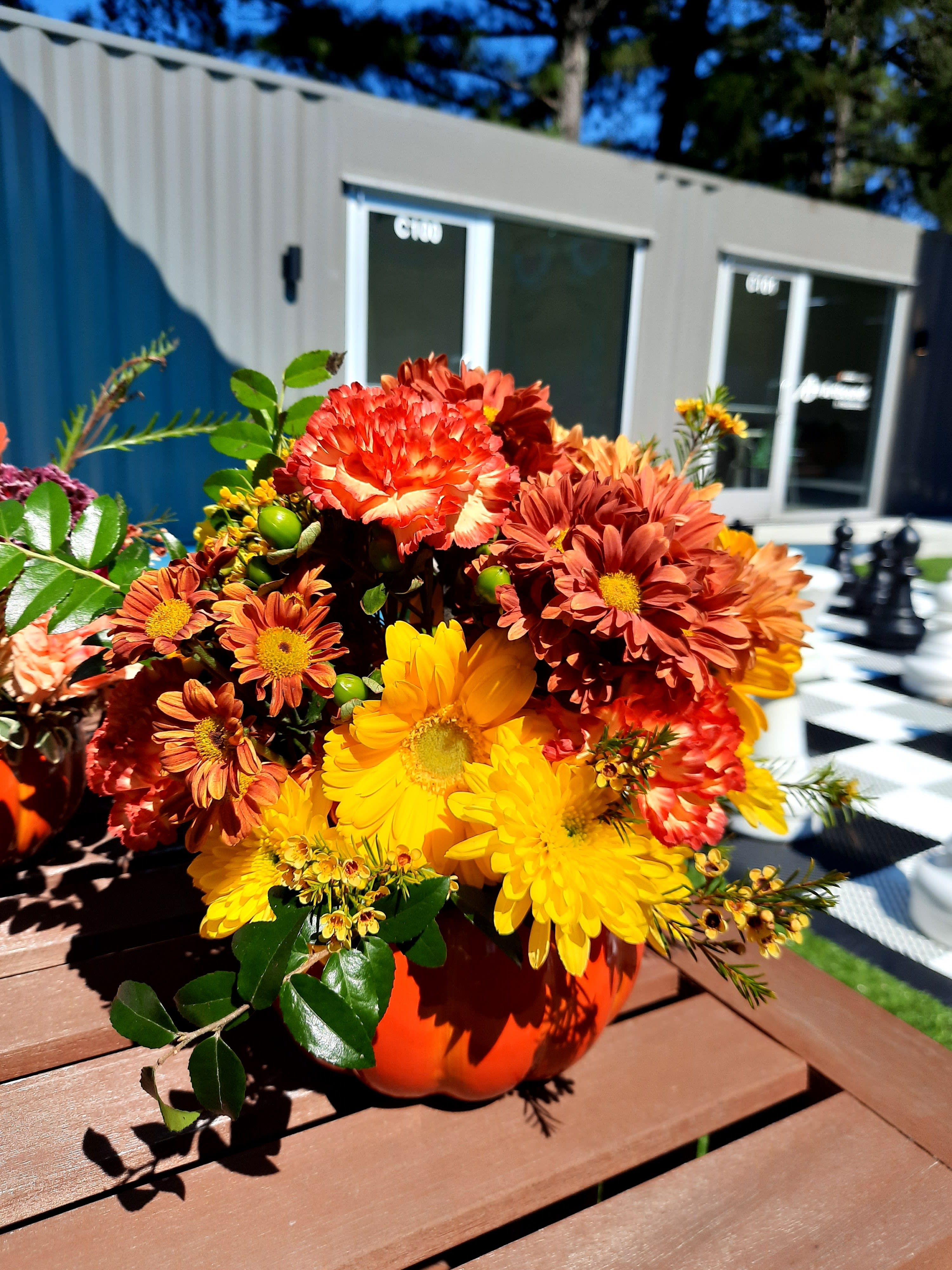 Orange and yellow chrysanthemum arrangement in a pumpkin-shaped vase