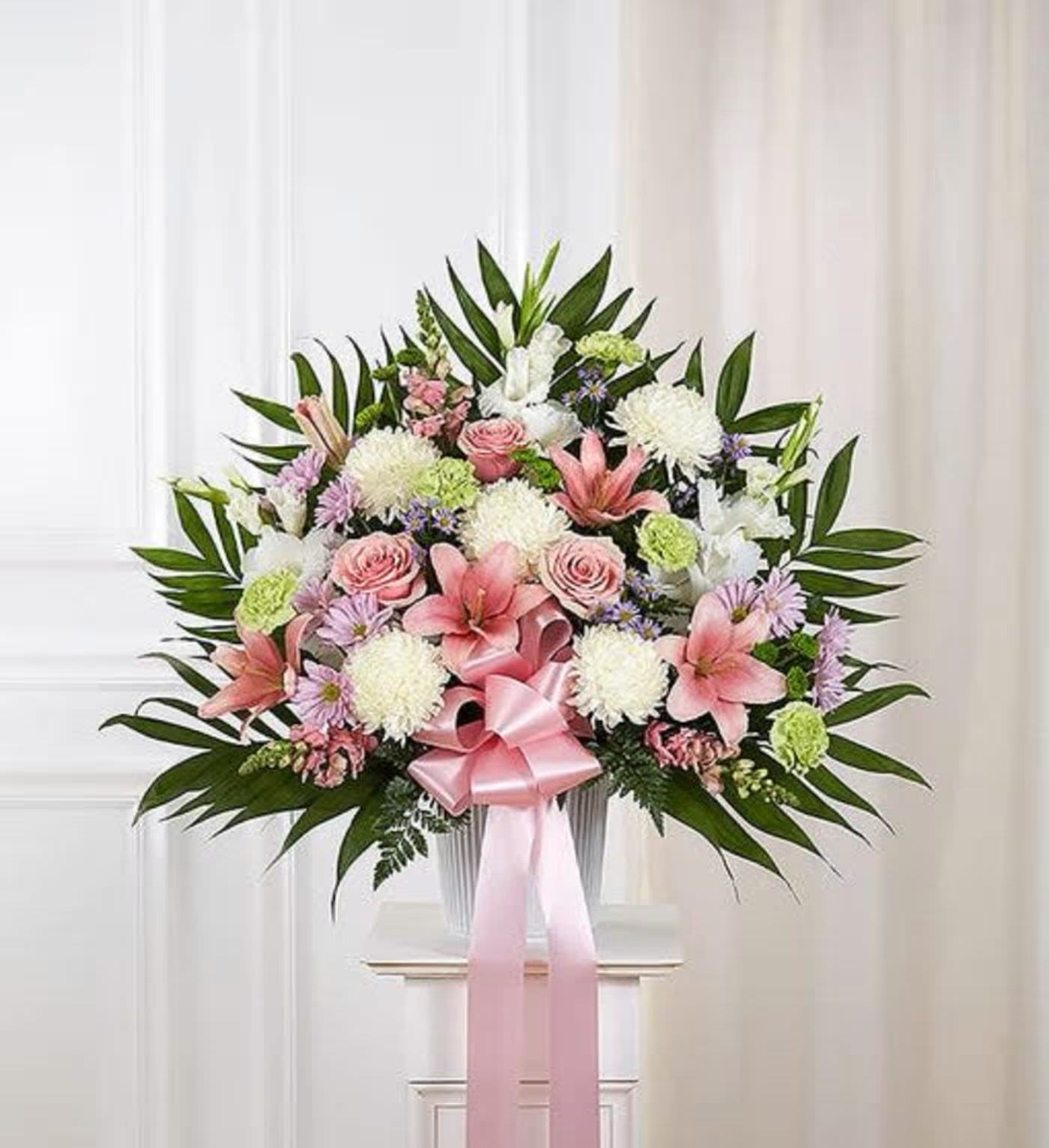Pink and white floral spray with a ribbon bow on a stand