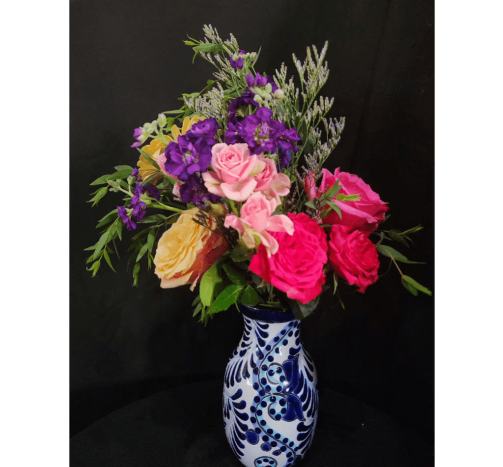 Mixed bouquet of roses and purple flowers in a blue-and-white vase