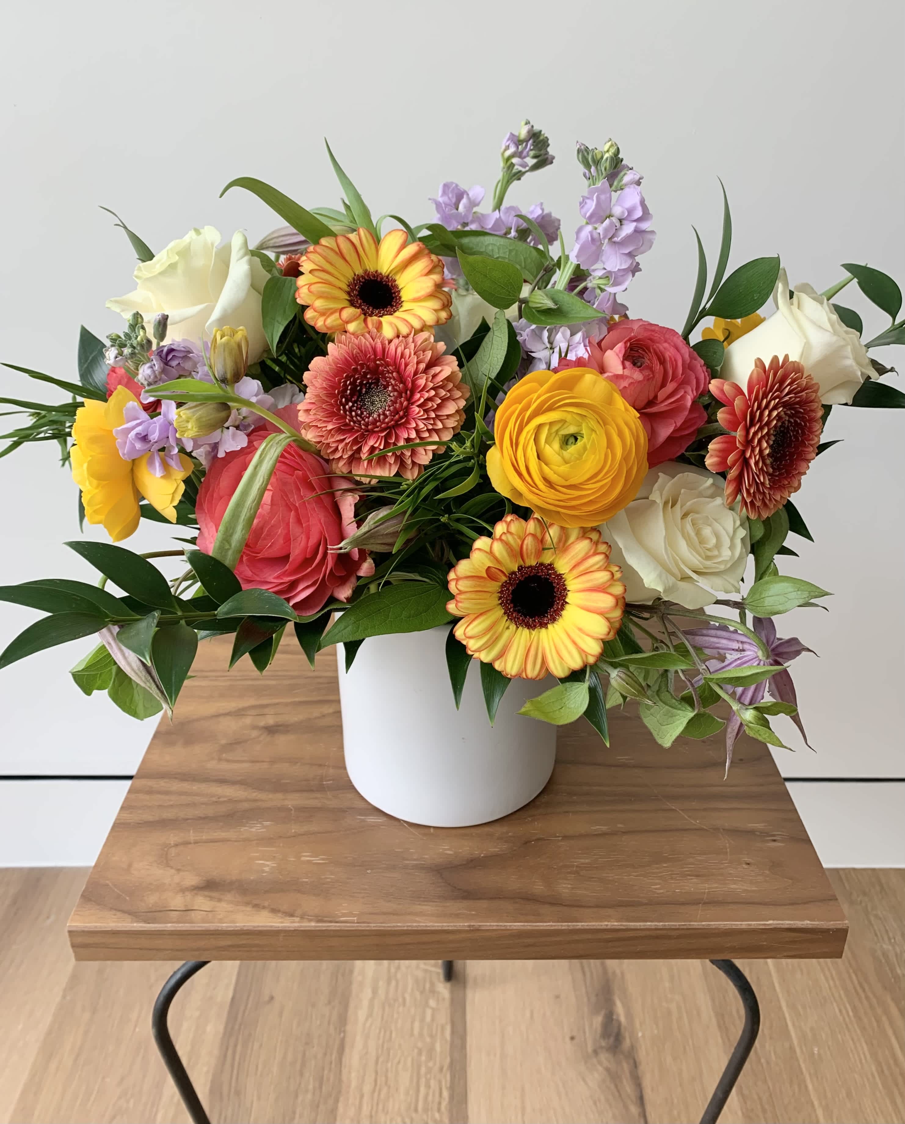 Mixed bouquet in a white vase with yellow, pink, white, and lavender flowers