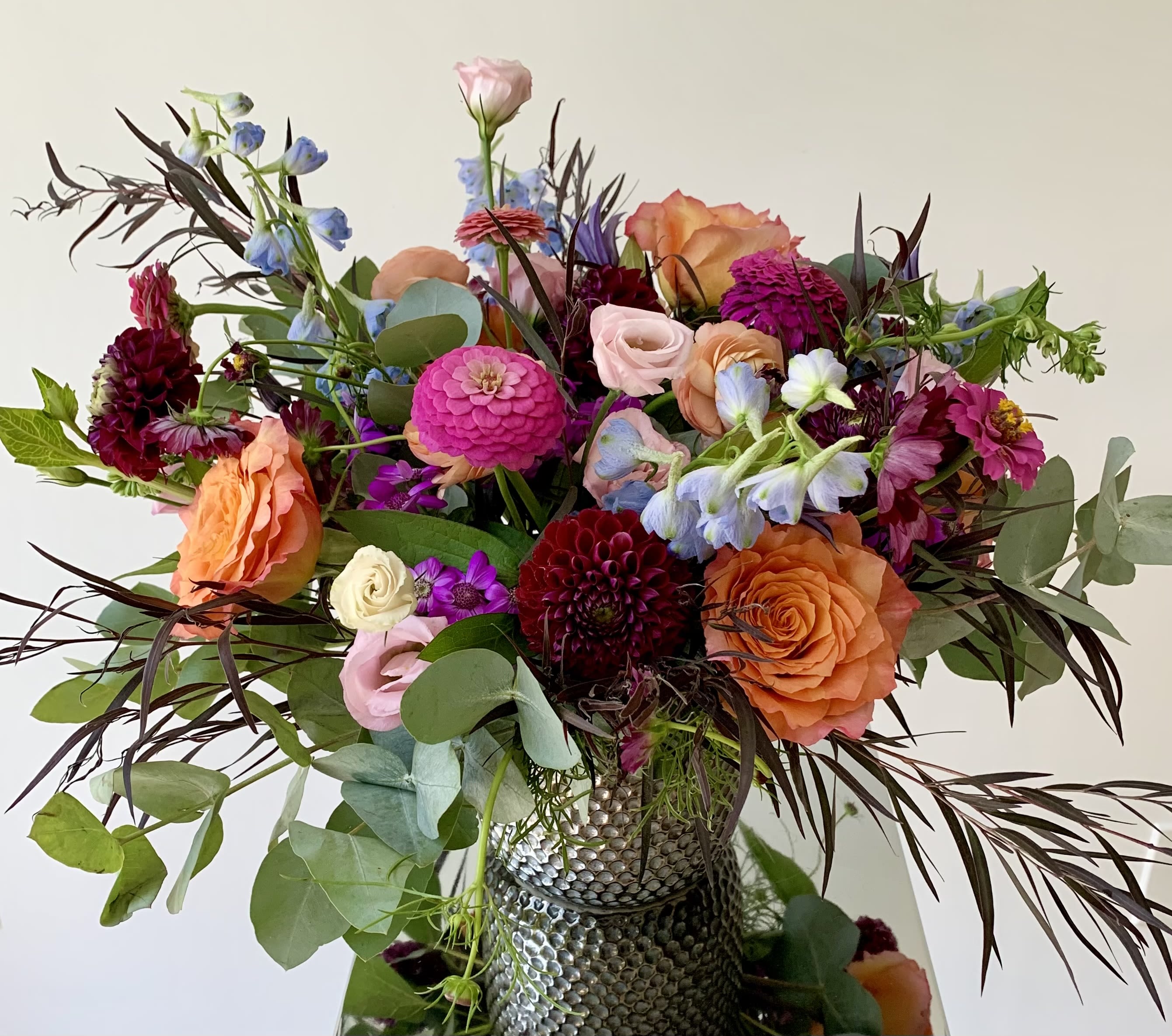 Mixed bouquet of orange, pink, and purple flowers in a textured vase
