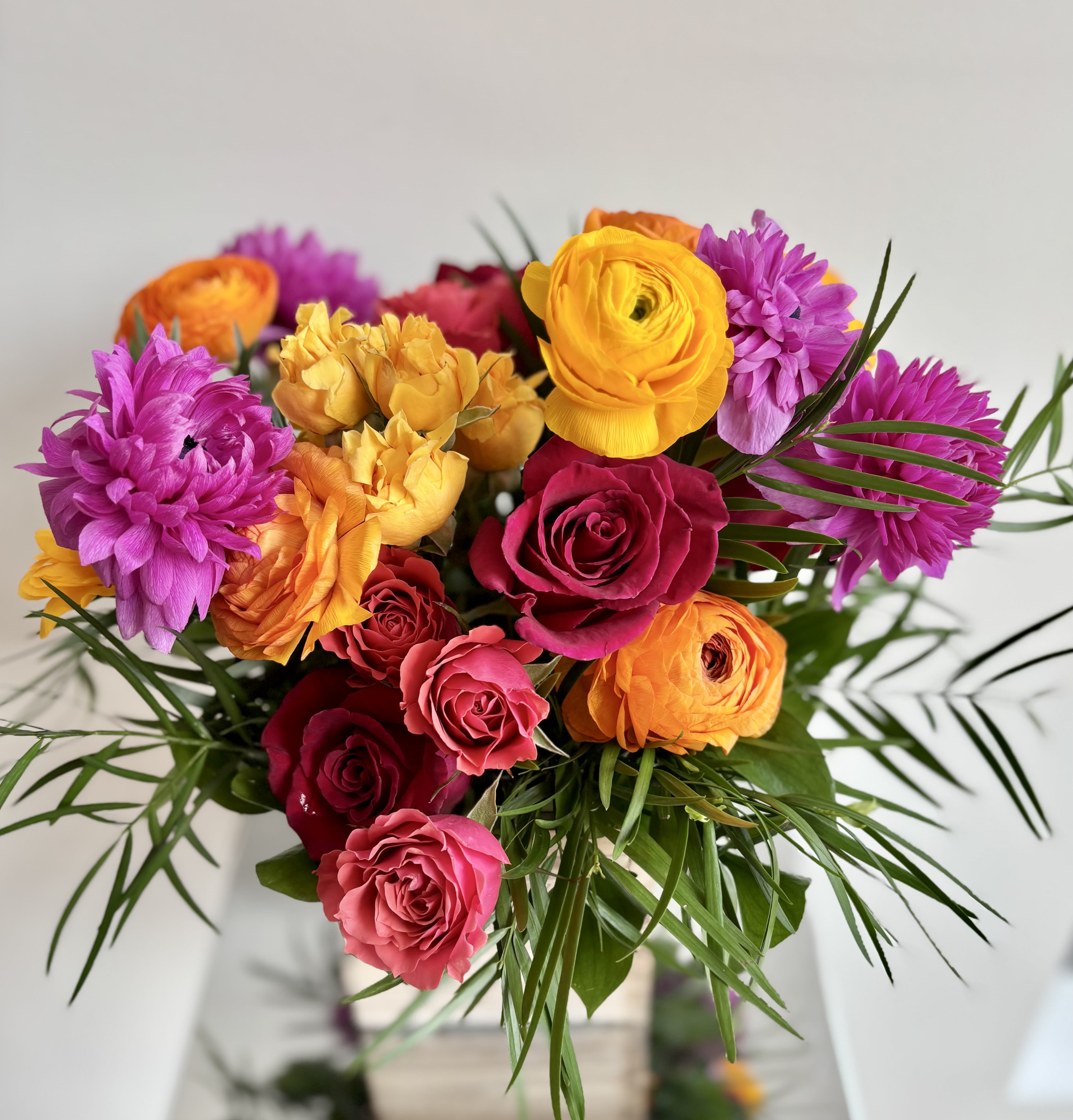 Bright bouquet of roses and purple blooms with palm-like greenery