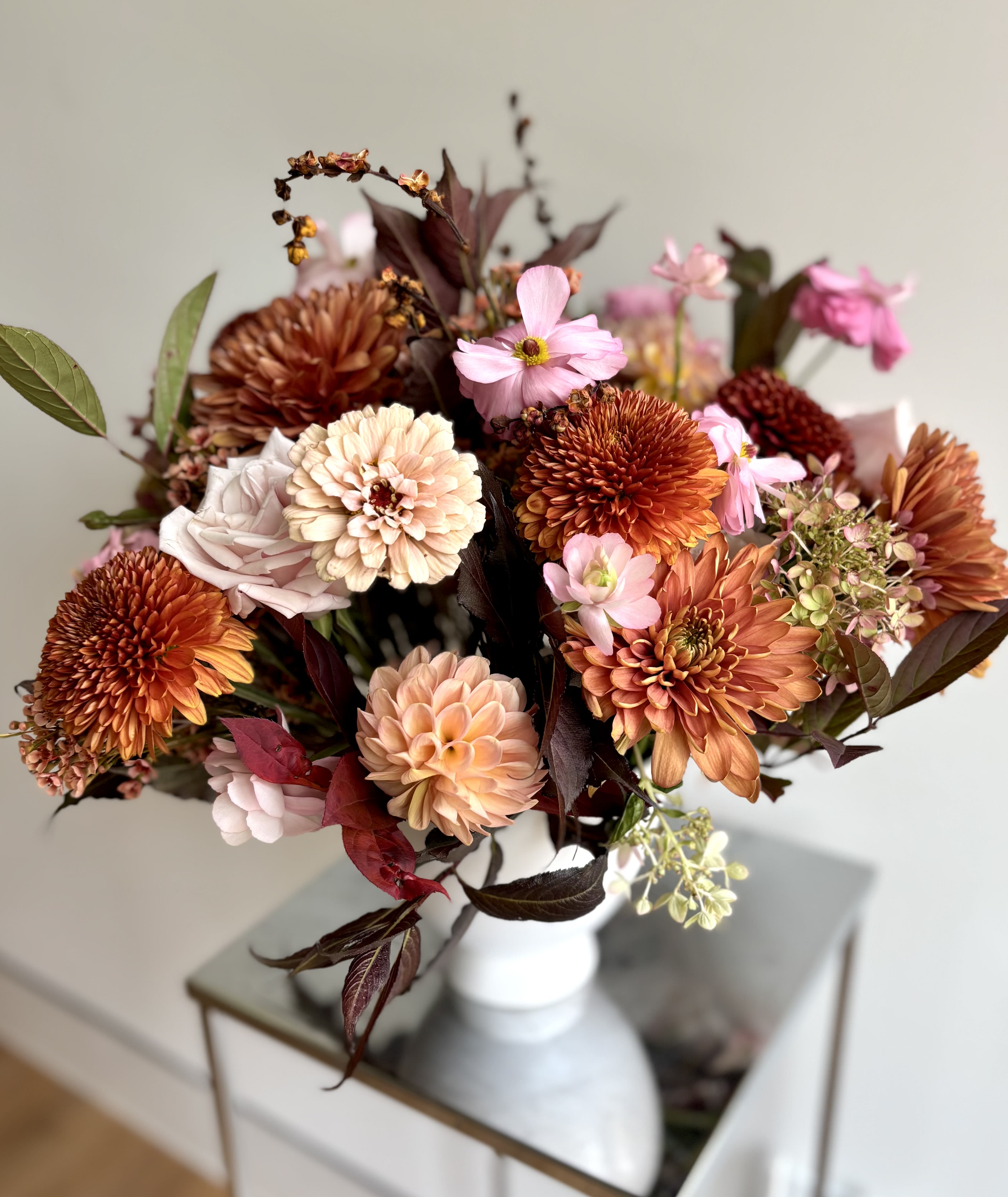 Bouquet of orange, pink, and cream flowers in a white vase