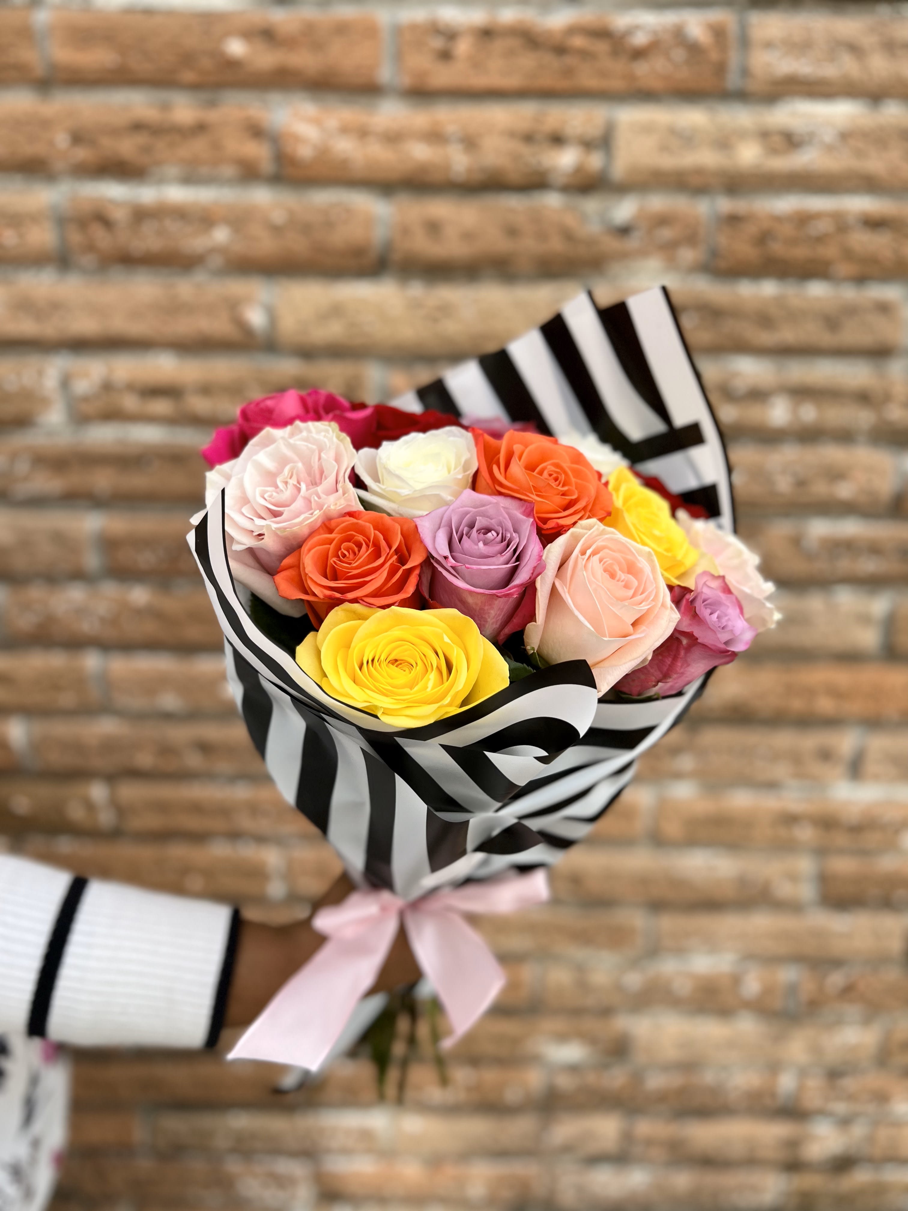 Bouquet of multicolored roses wrapped in black-and-white striped paper