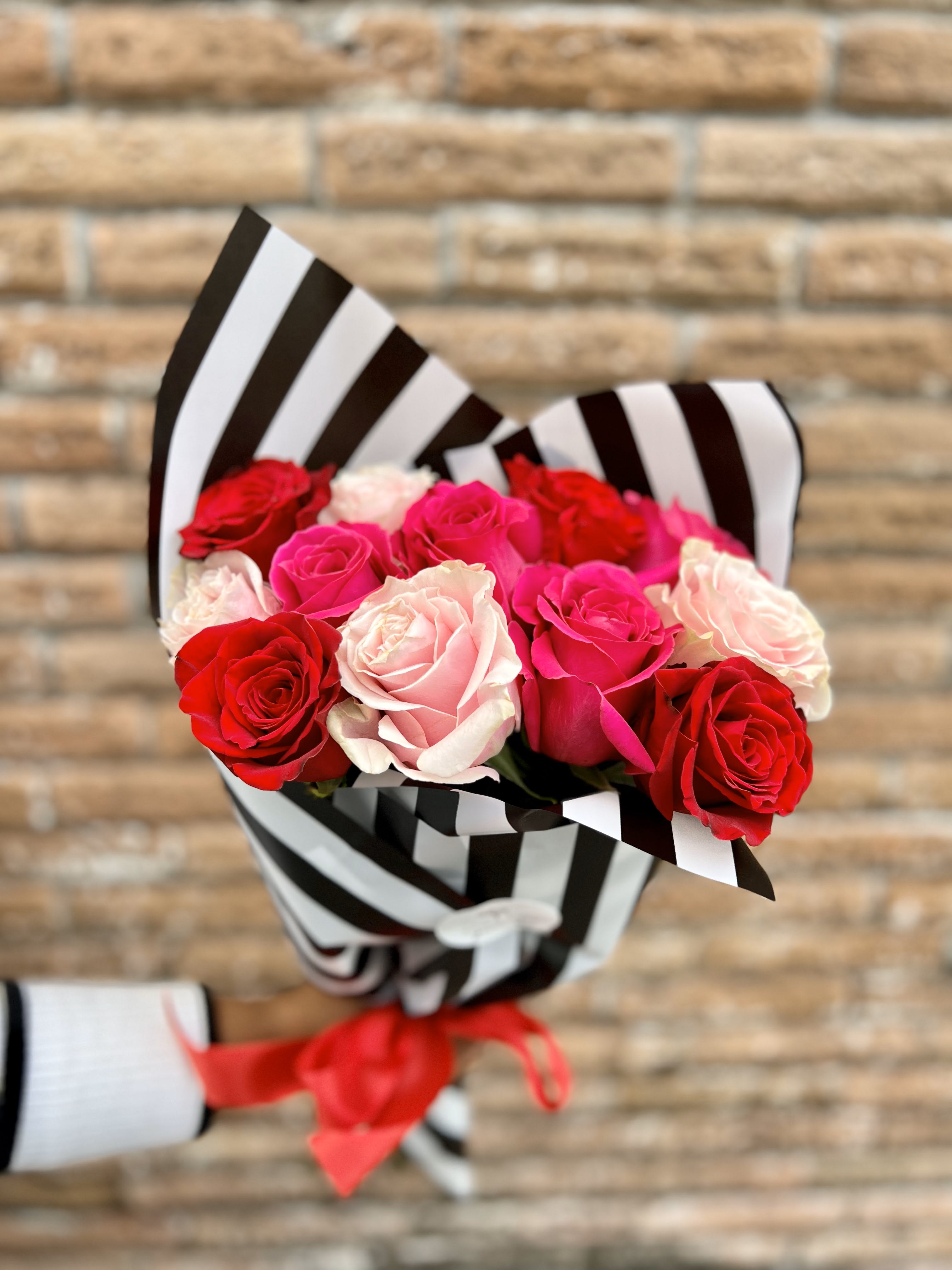 Bouquet of red, pink, and white roses wrapped in black-and-white striped paper