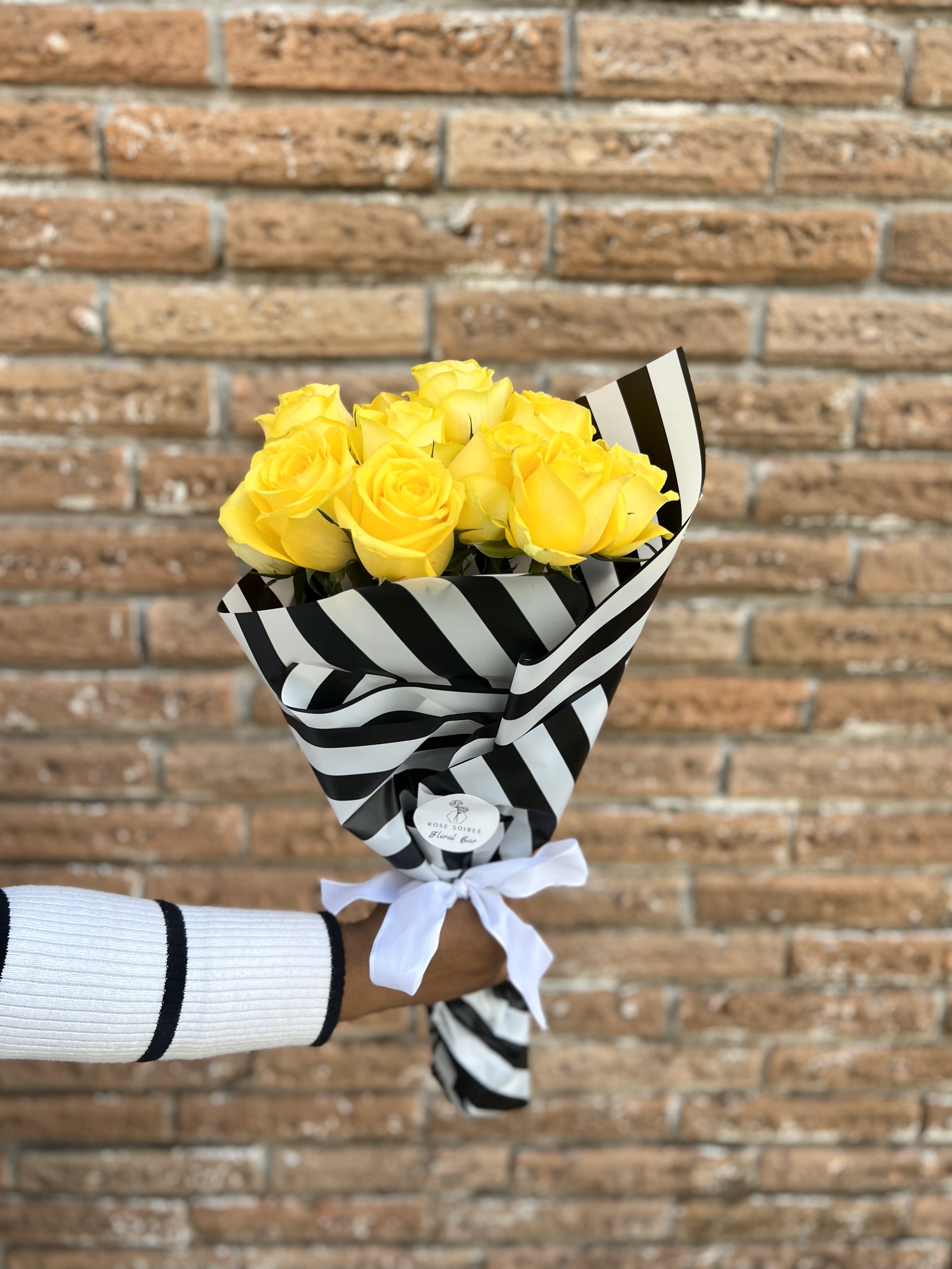 Bouquet of yellow roses wrapped in black-and-white striped paper