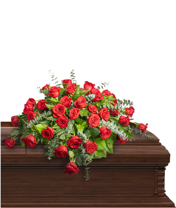 Red rose casket spray with greenery on a wooden casket