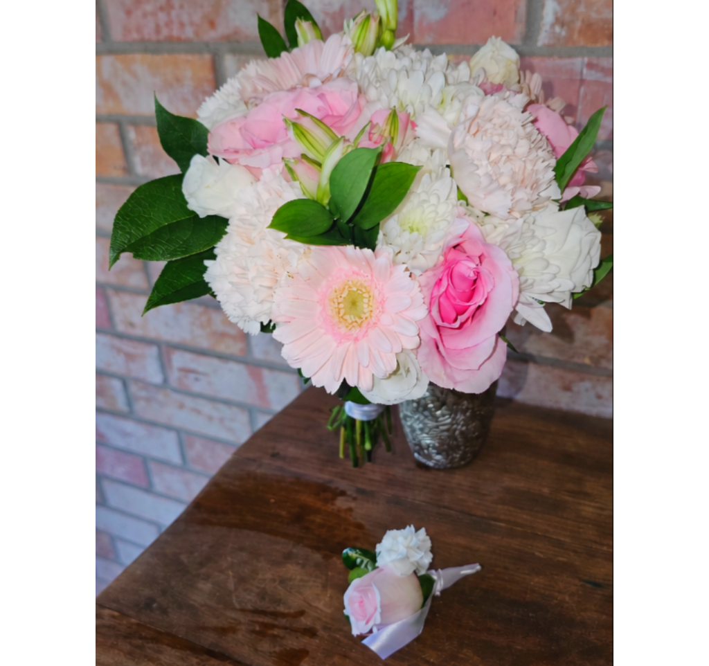 Pink and white bouquet in a silver vase with a matching boutonniere on a table