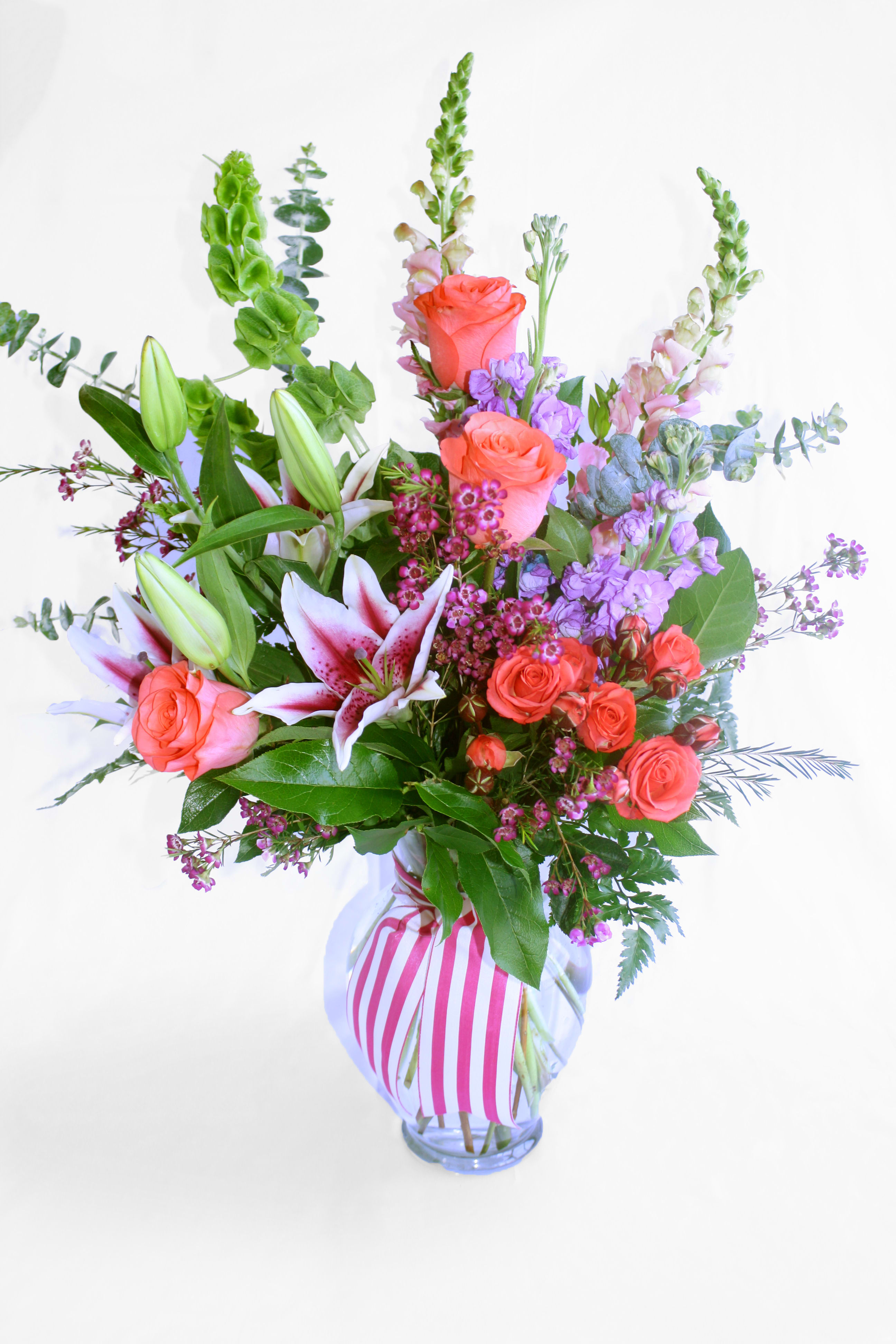 Mixed bouquet of pink roses and lilies in a striped glass vase