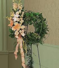 Floral wreath with pale flowers and pink ribbon on a stand