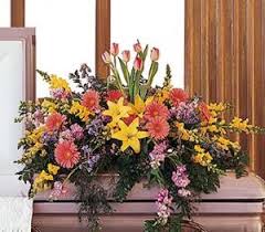 Large mixed floral arrangement with yellow lilies and pink blooms on a casket
