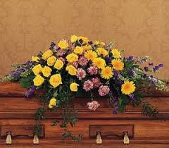 Yellow and pink floral arrangement on a wooden casket