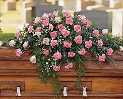 Pink and white carnations arranged on a wooden casket