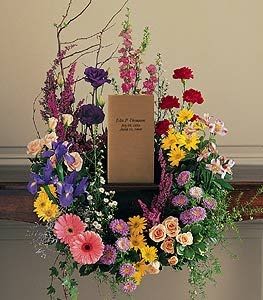 Large floral wreath with mixed colorful flowers around a central sign