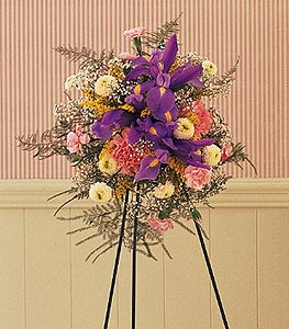 Standing floral spray with purple and pink flowers on a black easel