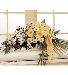 Yellow and white daisy arrangement with a yellow ribbon on a bed frame