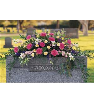 Pink and white floral arrangement on a gravestone