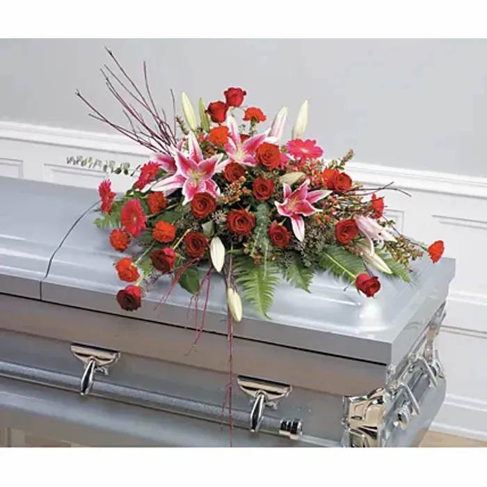 Red and pink floral casket spray on a silver casket