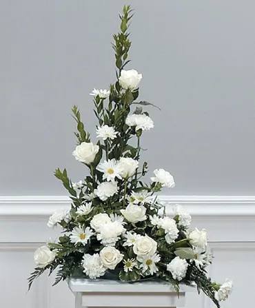 Tall white floral arrangement with roses and daisies on a stand