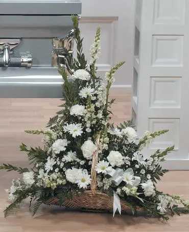White floral basket arrangement with tall spikes and a white ribbon