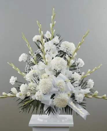 White funeral spray with ribbon on a stand