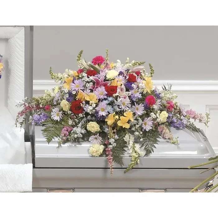 Large mixed flower spray on a white casket