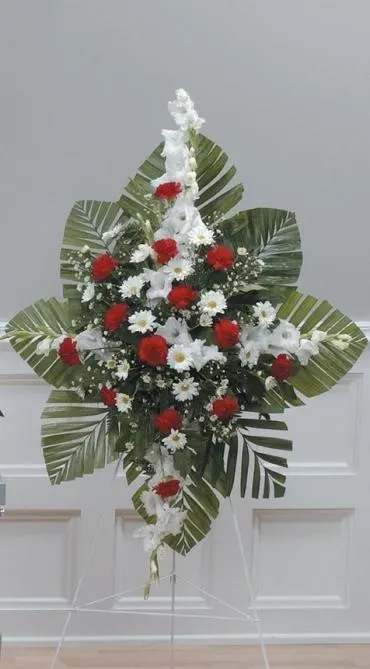 Standing floral spray with red and white flowers and large palm leaves
