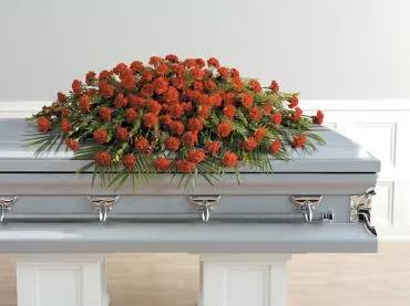 Red floral spray on top of a casket