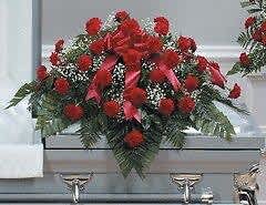 Red floral casket spray with greenery on a gray casket