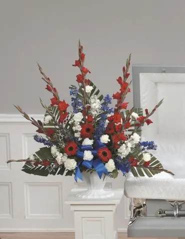 Tall red, white, and blue floral arrangement in a white pedestal vase