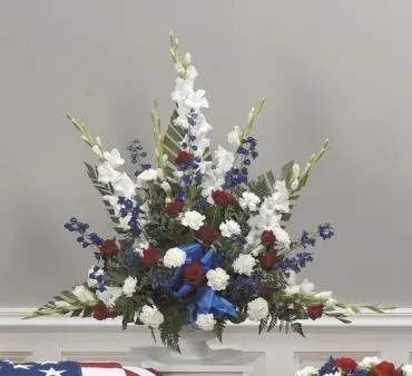 Red, white, and blue floral arrangement in a white vase
