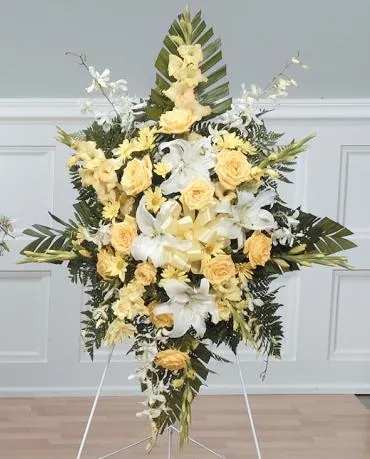 Standing floral spray with yellow roses and white lilies on an easel