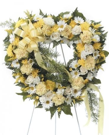 Heart-shaped floral wreath with yellow and white flowers on an easel