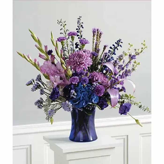 Purple and blue mixed flower arrangement in a dark blue vase