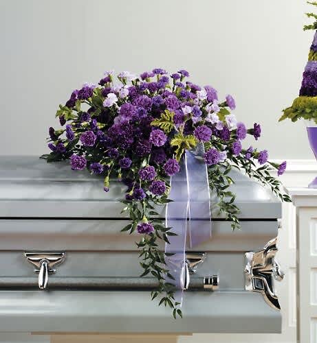Purple floral casket spray with trailing ribbon