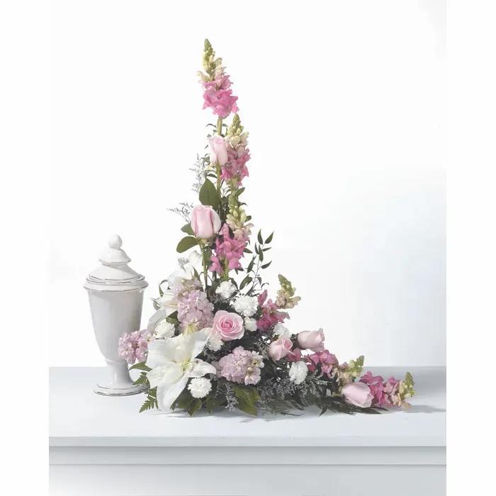 Pink and white floral spray beside a white urn
