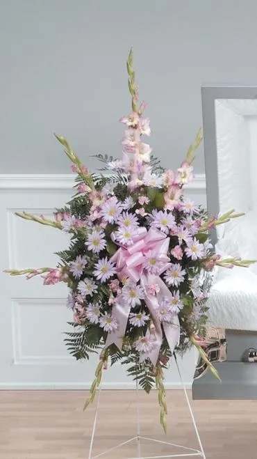 Standing floral spray with pink and lavender flowers on a white easel