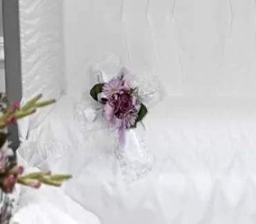 Small purple floral corsage on white fabric