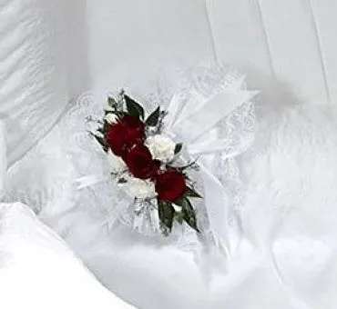 Small red and white floral corsage on white fabric