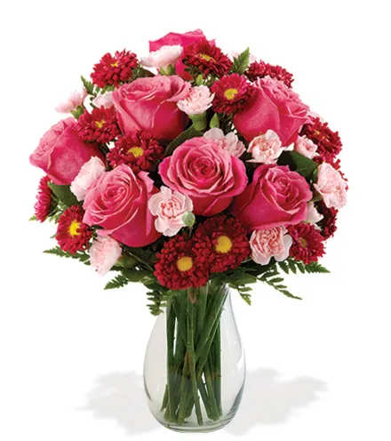 Pink roses and red daisy flowers in a clear glass vase