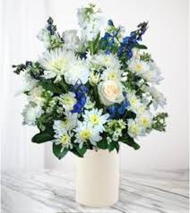 White and blue flowers arranged in a tall white vase