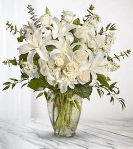 White lilies and roses arranged in a clear glass vase