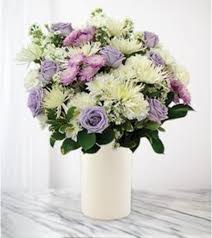 Lavender and white flowers arranged in a white vase