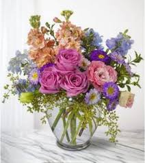Mixed bouquet of pink roses and purple flowers in a clear glass vase