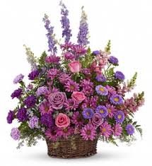 Purple and pink mixed flower arrangement in a wicker basket