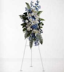 Blue and white funeral spray on a white easel
