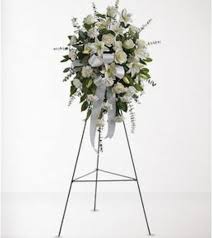 White floral standing spray on an easel with ribbon streamers