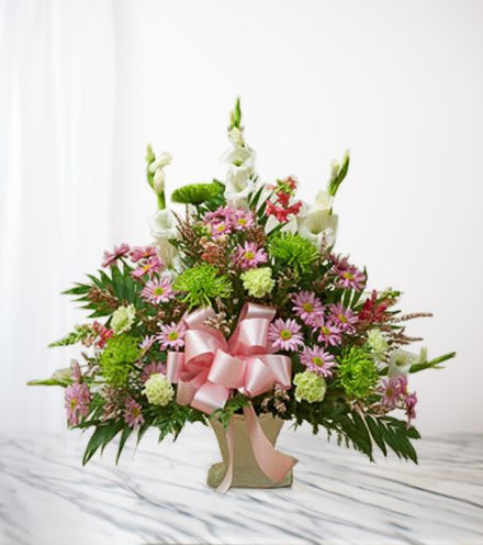 Pink and white mixed flower arrangement in a vase with a pink ribbon