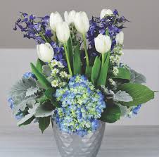 White tulips and blue flowers in a silver vase