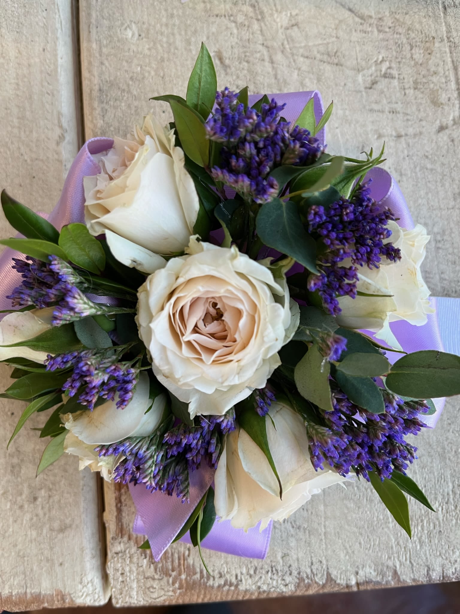 Bouquet of cream roses with purple filler flowers and lavender wrap